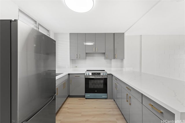 kitchen featuring kitchen peninsula, gray cabinets, stainless steel electric range oven, and black refrigerator