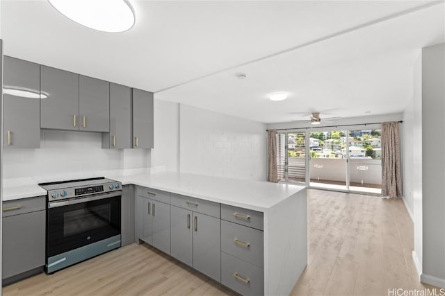 kitchen with gray cabinetry, stainless steel electric range, light hardwood / wood-style flooring, ceiling fan, and kitchen peninsula