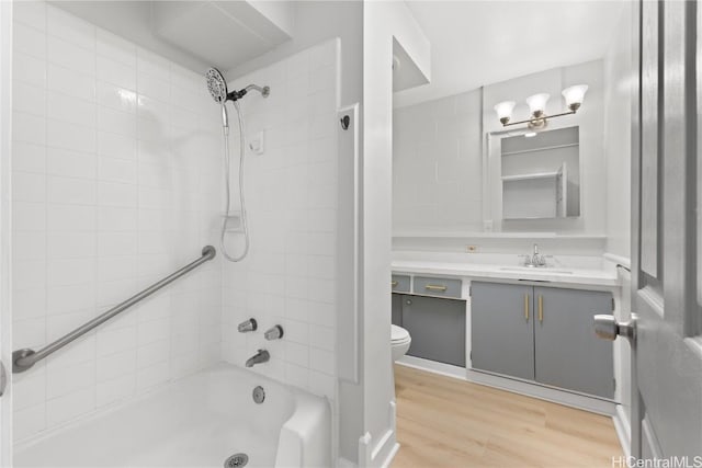 full bathroom featuring hardwood / wood-style floors, vanity, toilet, and tiled shower / bath