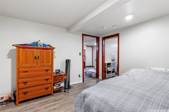 bedroom with beam ceiling, baseboards, and light wood finished floors