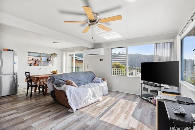 living area with ceiling fan, light wood finished floors, and a wall mounted AC