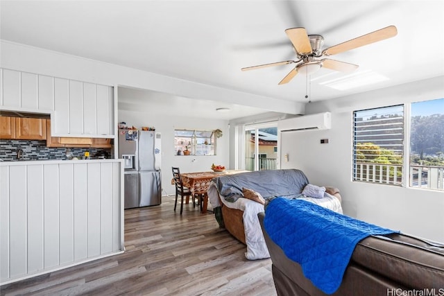 interior space featuring ceiling fan, an AC wall unit, and light wood-style floors