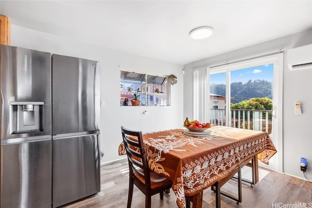 dining space with an AC wall unit and wood finished floors