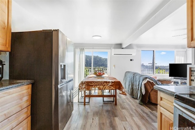 kitchen with dark countertops, a wall mounted air conditioner, light wood-type flooring, stainless steel refrigerator with ice dispenser, and beam ceiling