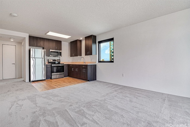 615 Keawe St Unit 406, Honolulu, HI 96813 - kitchen with a textured ceiling, dark brown cabinetry, appliances with stainless steel finishes, light carpet, and sink