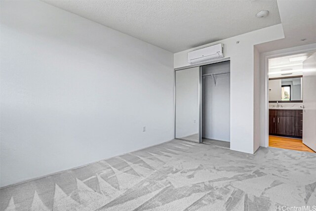 615 Keawe St Unit 406, Honolulu, HI 96813 - unfurnished bedroom featuring a closet, light carpet, a wall unit AC, a textured ceiling, and sink