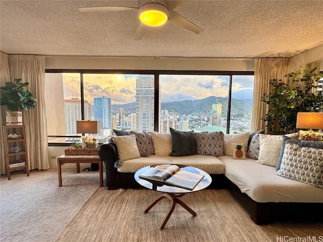 sunroom / solarium featuring ceiling fan, carpet flooring, a mountain view, and a textured ceiling