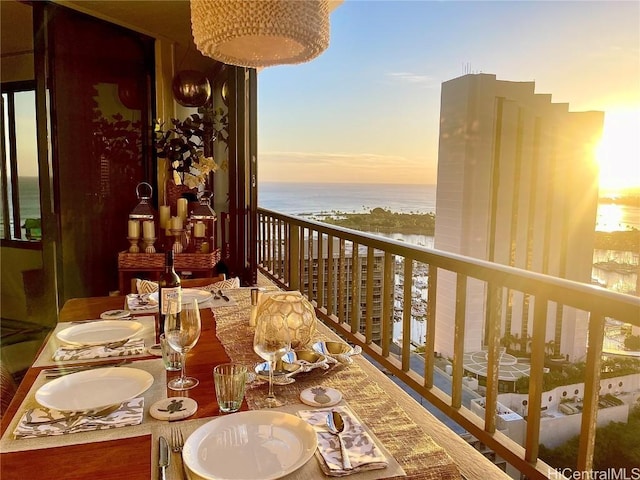 balcony at dusk featuring a water view