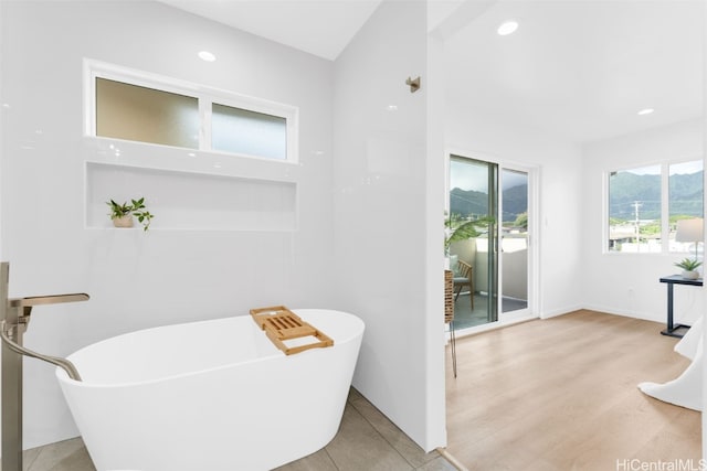 bathroom with a soaking tub, recessed lighting, and wood finished floors