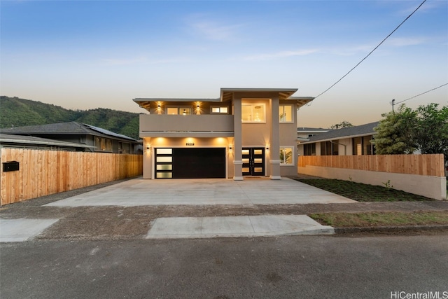 view of front of house featuring stucco siding, an attached garage, concrete driveway, and fence