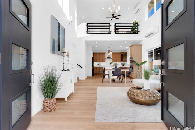 entryway with a wall mounted air conditioner, ceiling fan, a high ceiling, and light hardwood / wood-style flooring