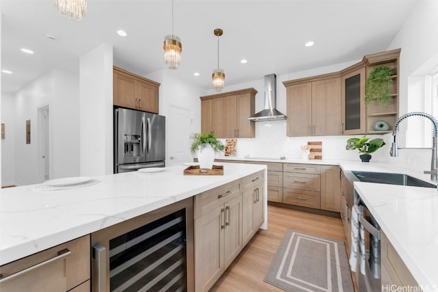 kitchen with stainless steel appliances, beverage cooler, wall chimney range hood, decorative light fixtures, and light hardwood / wood-style floors