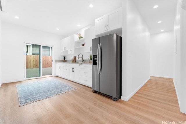 kitchen with white cabinets, stainless steel fridge with ice dispenser, and light hardwood / wood-style flooring