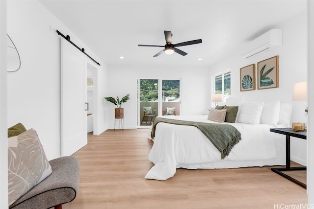 bedroom featuring a wall unit AC, a barn door, ceiling fan, and light wood-type flooring