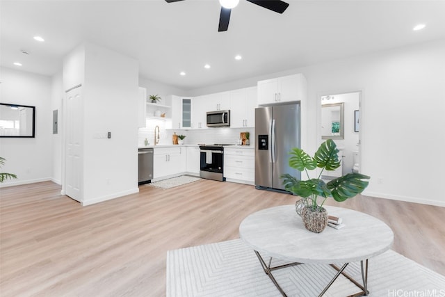 kitchen featuring backsplash, white cabinetry, light wood-type flooring, and stainless steel appliances