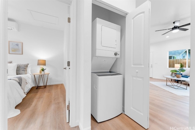 washroom with an AC wall unit, attic access, laundry area, light wood-style flooring, and stacked washer and clothes dryer