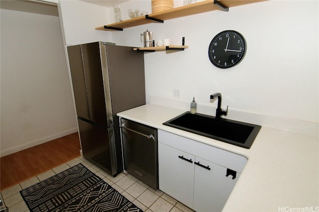 kitchen with light tile patterned floors, stainless steel appliances, white cabinetry, and sink