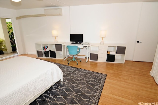 bedroom with an AC wall unit and hardwood / wood-style floors