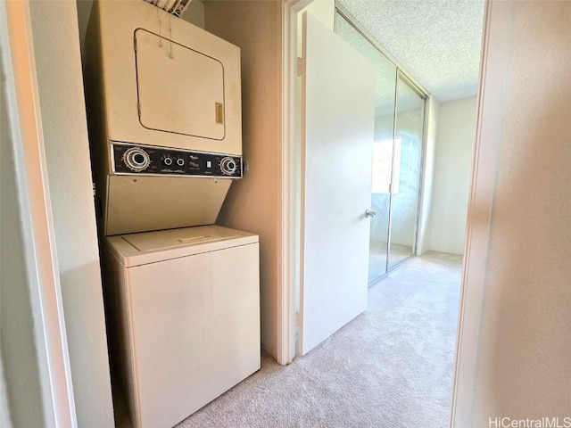 clothes washing area featuring a textured ceiling, stacked washer and clothes dryer, and light colored carpet