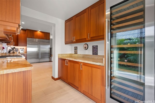 kitchen with stainless steel built in refrigerator, sink, and beverage cooler