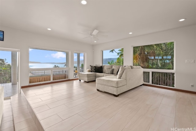 living room featuring ceiling fan and a water view