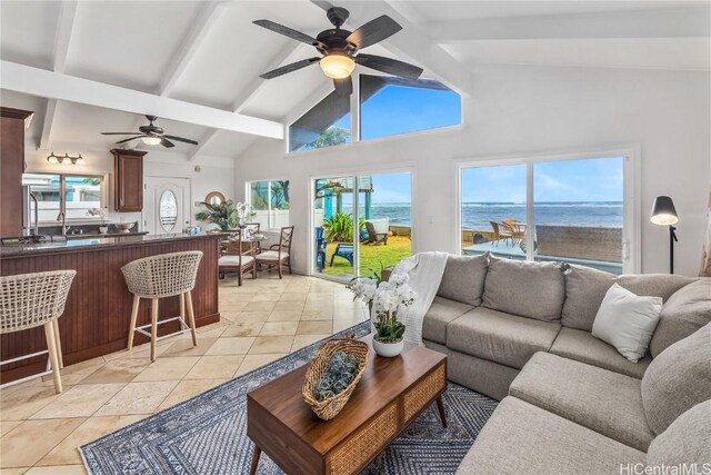 living room with beamed ceiling, ceiling fan, a water view, and light tile patterned floors