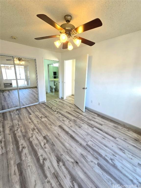 unfurnished bedroom with light wood-type flooring, a textured ceiling, and ceiling fan