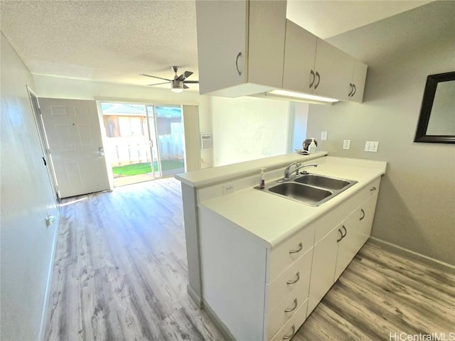 kitchen with kitchen peninsula, ceiling fan, sink, and a textured ceiling