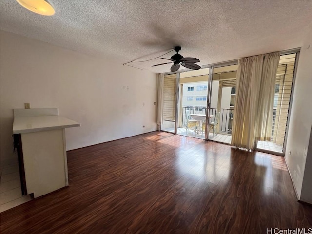 unfurnished room featuring dark hardwood / wood-style flooring, a textured ceiling, expansive windows, and ceiling fan