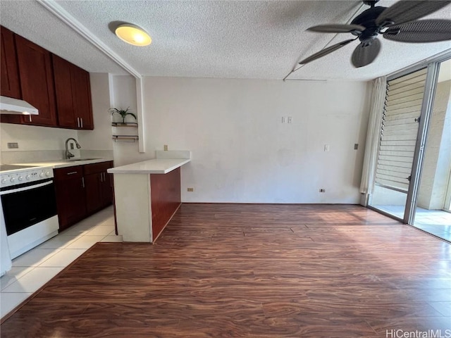 kitchen featuring sink, stove, kitchen peninsula, a textured ceiling, and light hardwood / wood-style flooring