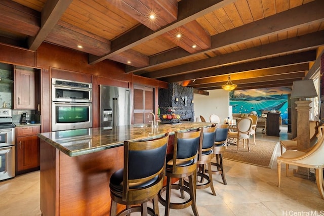 kitchen featuring beamed ceiling, a spacious island, wood ceiling, and appliances with stainless steel finishes