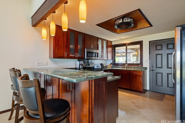 kitchen featuring a breakfast bar, dark stone countertops, appliances with stainless steel finishes, decorative light fixtures, and kitchen peninsula