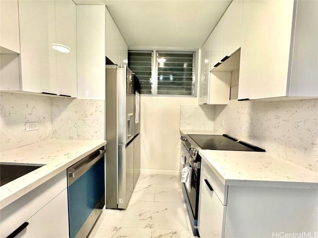 kitchen featuring white cabinets, appliances with stainless steel finishes, backsplash, and light stone countertops