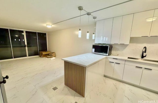 kitchen featuring white cabinets, pendant lighting, tasteful backsplash, and sink