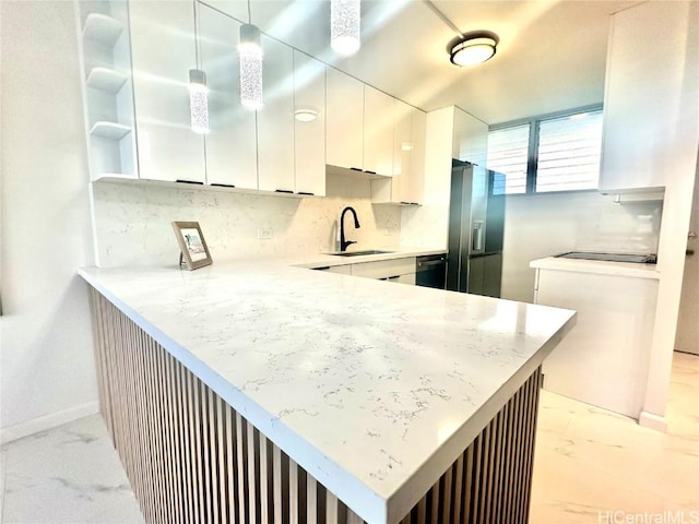 kitchen with sink, kitchen peninsula, stainless steel fridge, decorative light fixtures, and white cabinetry