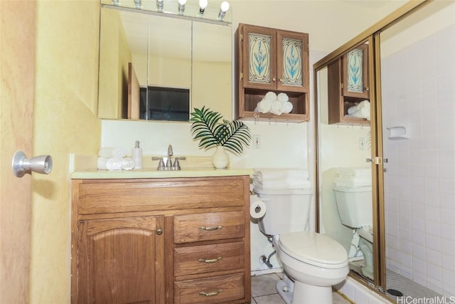 bathroom with tile patterned flooring, vanity, a shower with shower door, and toilet