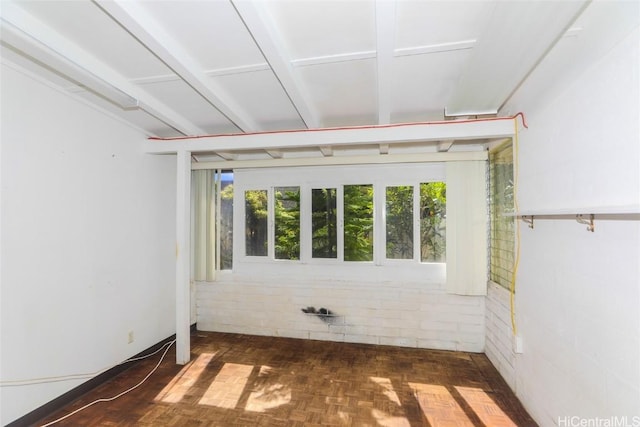 unfurnished room featuring dark parquet flooring and brick wall