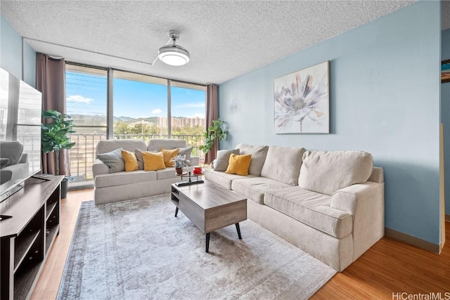 living room featuring hardwood / wood-style floors, a wall of windows, and a textured ceiling