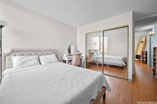 bedroom with hardwood / wood-style floors, a textured ceiling, and a closet