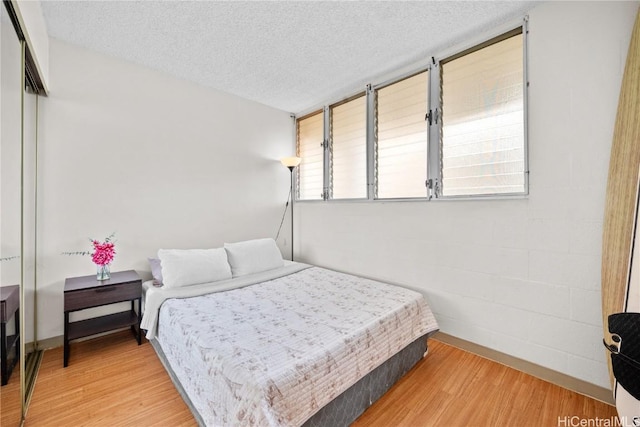 bedroom with hardwood / wood-style floors, a textured ceiling, and a closet