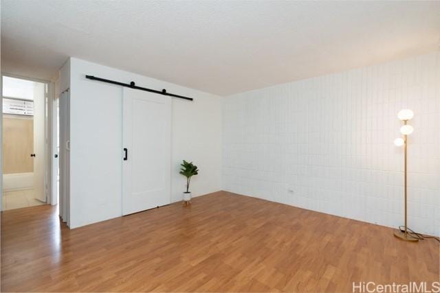 unfurnished bedroom with wood-type flooring and a barn door