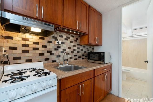 kitchen featuring tasteful backsplash, sink, light tile patterned floors, and white gas range oven