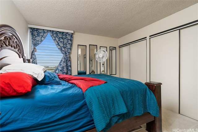 bedroom featuring two closets, light carpet, and a textured ceiling