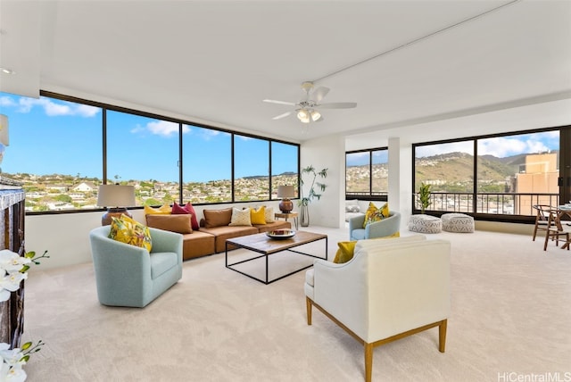 carpeted living room with ceiling fan and a mountain view