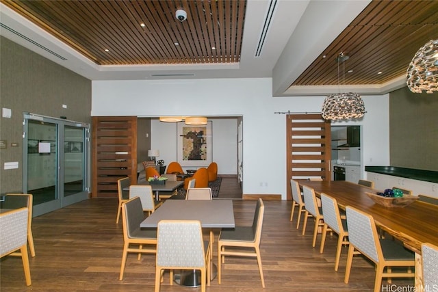 dining area with dark hardwood / wood-style floors, a barn door, a raised ceiling, and wood ceiling