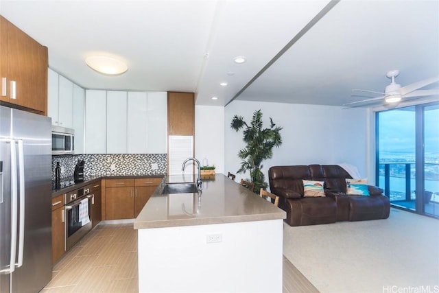 kitchen featuring ceiling fan, sink, stainless steel appliances, tasteful backsplash, and white cabinets