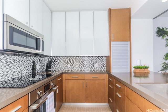 kitchen featuring white cabinets, backsplash, and stainless steel appliances