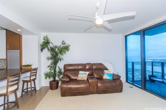 living room featuring ceiling fan, expansive windows, and light wood-type flooring