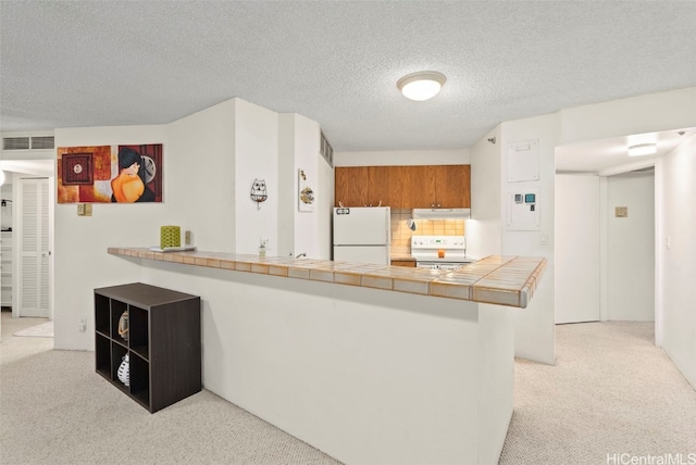 kitchen featuring tile countertops, kitchen peninsula, white fridge, a textured ceiling, and range