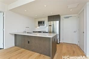 kitchen with kitchen peninsula, appliances with stainless steel finishes, light wood-type flooring, dark brown cabinets, and sink